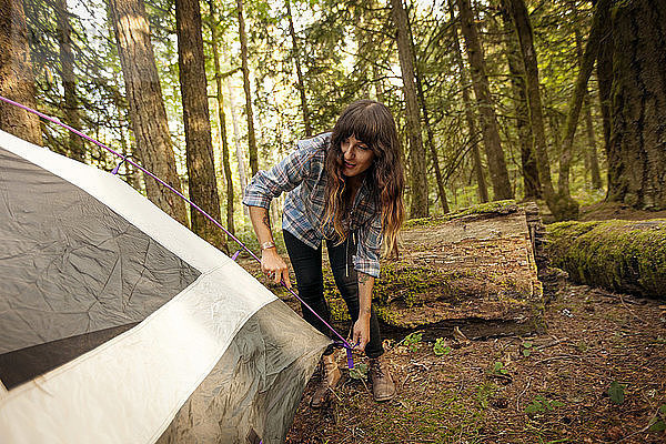 Frau bereitet Zelt im Wald vor
