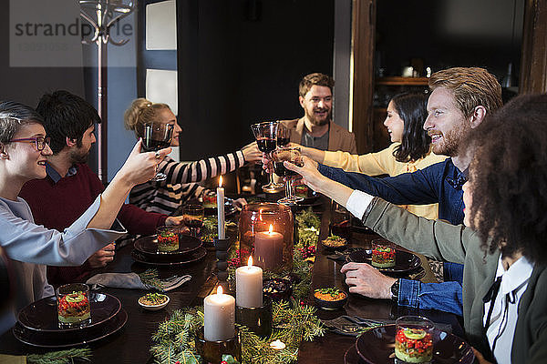 Freunde stoßen auf der Weihnachtsfeier beim Essen auf Wein an