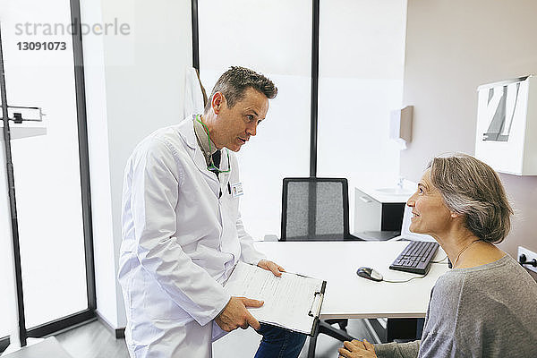Arzt spricht mit Patient  während er in einer medizinischen Klinik sitzt