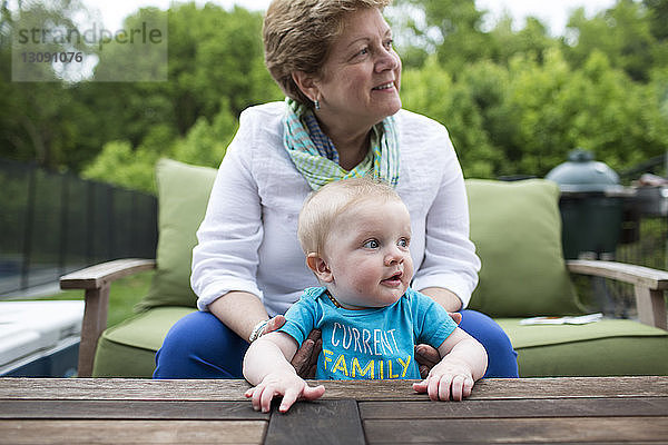 Großmutter schaut weg  während sie den Enkel im Hof hält