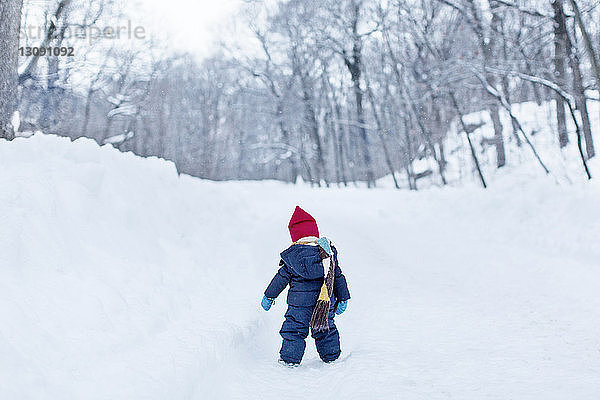 Rückansicht eines kleinen Mädchens  das auf einem schneebedeckten Feld steht