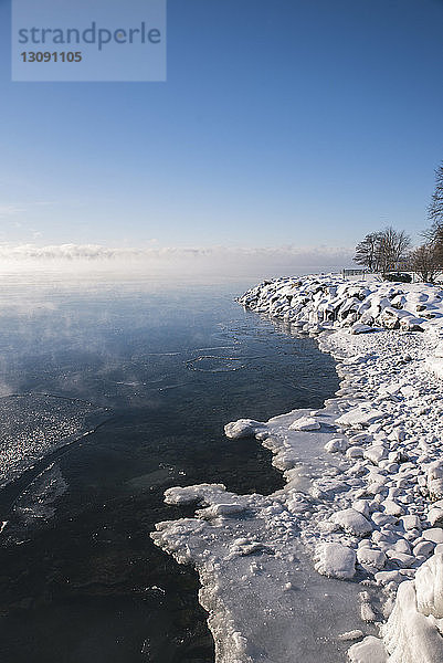 Idyllischer Anblick eines zugefrorenen Sees gegen den Himmel bei nebligem Wetter