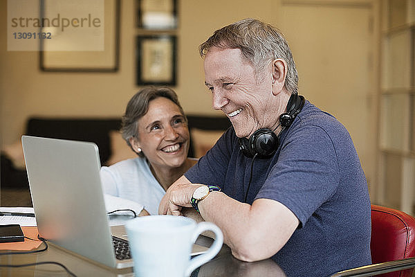 Fröhliches älteres Ehepaar mit Laptop zu Hause