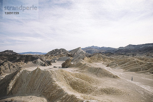 Mitteldistanzansicht eines Wanderers inmitten der Wüste vor bewölktem Himmel im Death Valley National Park