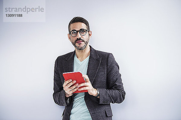 Porträt eines Geschäftsmannes  der ein digitales Tablet hält und im Kreativbüro steht