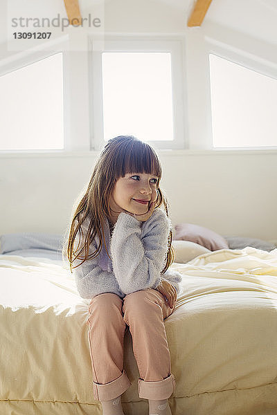 Nachdenkliches Mädchen sitzt zu Hause auf dem Bett