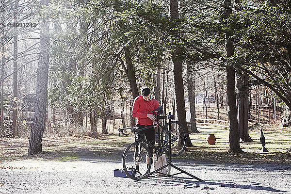 Sportler  der bei Sonnenschein sein Fahrrad auf der Straße einstellt