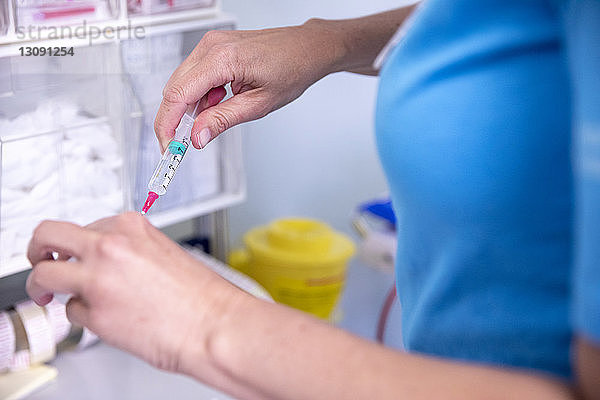 Mittelteil einer Ärztin  die im Krankenhaus stehend eine Spritze hält