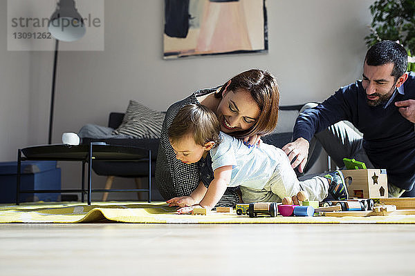 Eltern und Sohn spielen zu Hause mit der Spielzeugeisenbahn