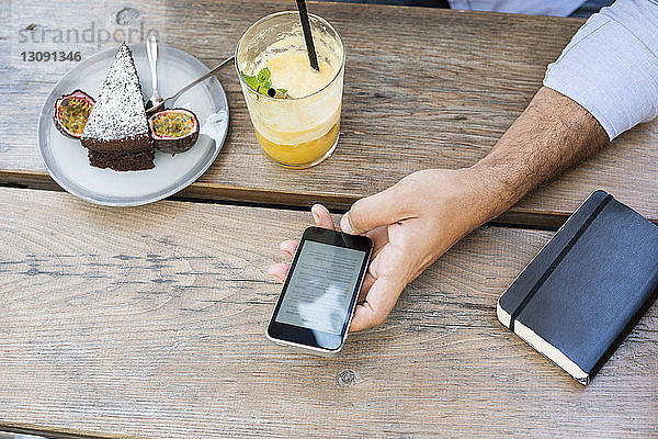 Draufsicht eines Mannes  der ein Smartphone im Straßencafé benutzt
