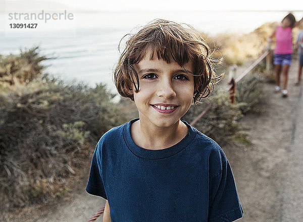 Porträt eines lächelnden Mädchens  das auf einem Feld gegen das Meer steht
