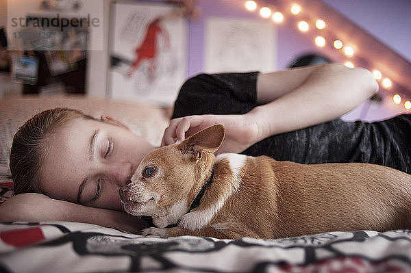 Mädchen mit Chihuahua entspannt sich zu Hause im Bett