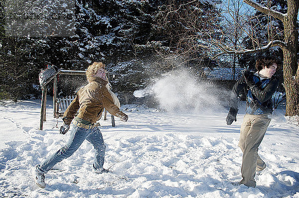 Spielerischer Mann wirft Schneeball auf Bruder im Hinterhof