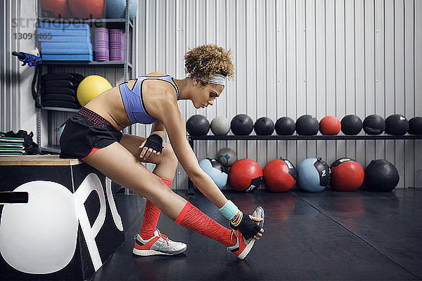 Seitenansicht einer Sportlerin  die auf einer Box sitzend im Fitnessstudio trainiert