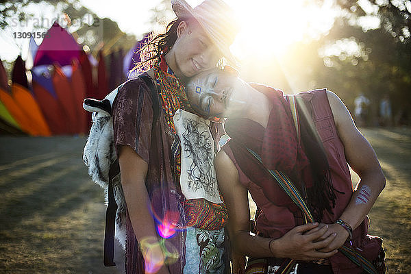 Lächelnde Freunde umarmen sich im Stehen bei einer traditionellen Veranstaltung