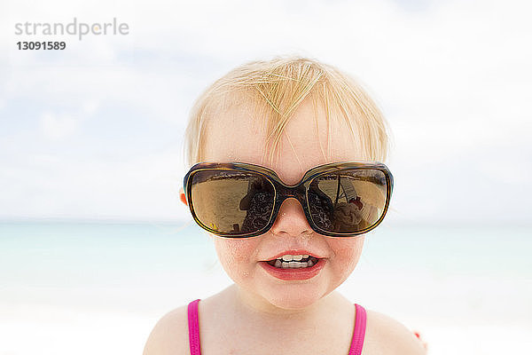 Nahaufnahme eines fröhlichen Mädchens mit Sonnenbrille gegen das Meer