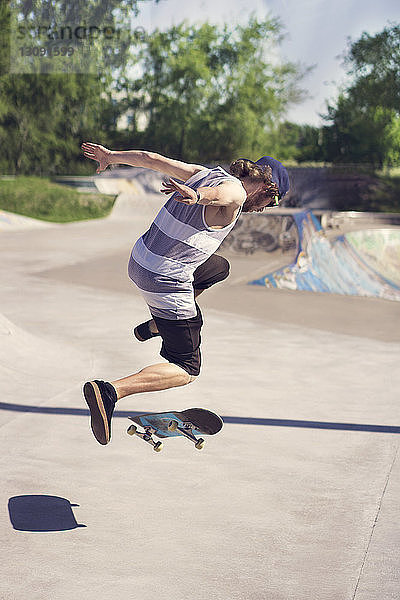 Junger Mann macht Skateboardtrick auf Rampe