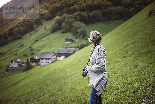 Frau hält Kamera  während sie auf einem Hügel steht
