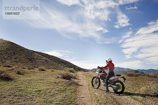 Seitenansicht einer Motorradfahrerin  die auf einem Motorrad auf dem Land sitzt