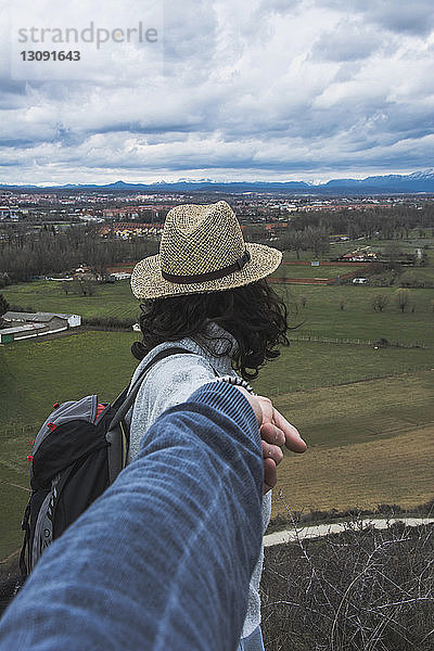 Ausgeschnittenes Bild eines Freundes  der die Hand seiner Freundin gegen den bewölkten Himmel hält