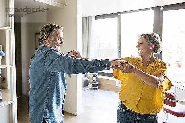 Fröhliches Seniorenpaar tanzt zu Hause