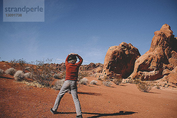 Junge steht bei sonnigem Wetter im Valley of Fire State Park vor Felsformationen und Himmel