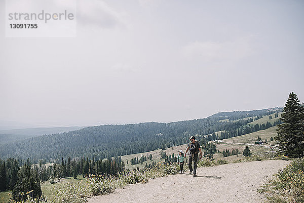 Vater und Tochter in voller Länge auf unbefestigter Straße gegen den Himmel im Yellowstone-Nationalpark