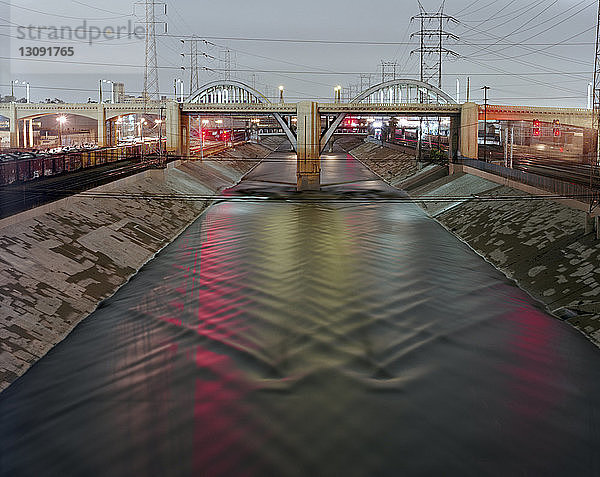 Beleuchtete Brücke über den Fluss in der Stadt in der Abenddämmerung