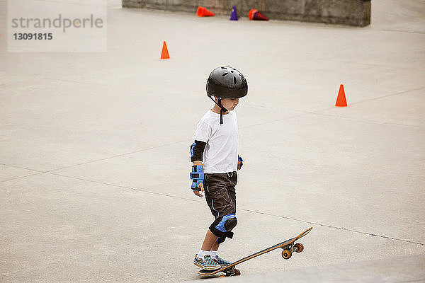 Junge steht mit Skateboard auf Rampe