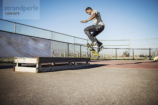 Mann fährt Skateboard im Skateboard-Park gegen klaren Himmel