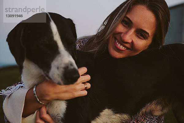 Porträt einer glücklichen Frau  die einen Hund im Freien umarmt