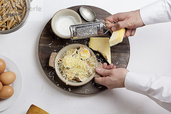 Draufsicht des Küchenchefs  der Käse auf gekochten Eiern in einer Schüssel reibt