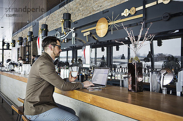 Geschäftsmann arbeitet am Laptop am Café-Schalter