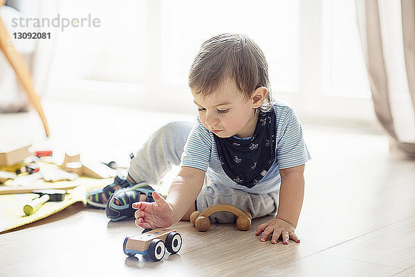 Kleiner Junge spielt mit Spielzeug  während er zu Hause auf dem Boden sitzt