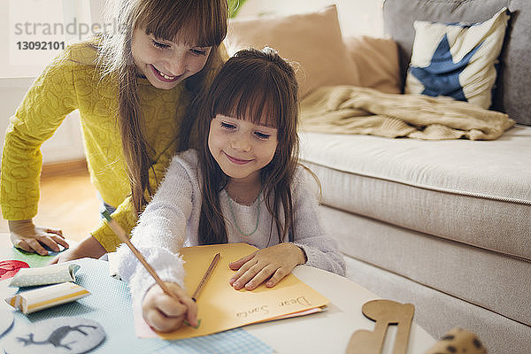 Schwester für Mädchen schreibt zu Hause auf Papier