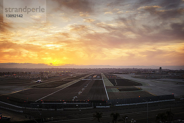 Startbahn des Flughafens gegen bewölkten Himmel bei Sonnenuntergang