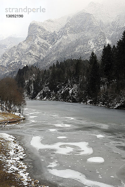 Landschaftliche Ansicht eines zugefrorenen Sees vor den Bergen im Winter