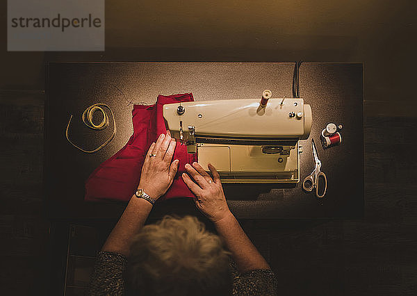 Hochwinkelansicht einer Frau  die in der Werkstatt eine Nähmaschine benutzt