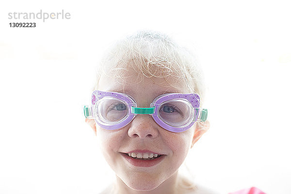 Porträt eines lächelnden Mädchens mit Schwimmbrille gegen den Himmel während eines sonnigen Tages