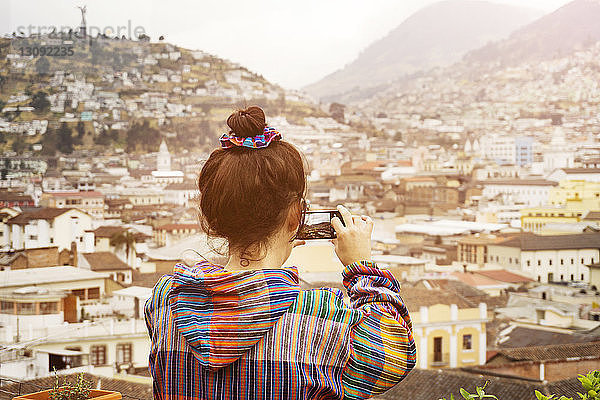 Rückansicht einer Frau  die an einem sonnigen Tag ein Wohnviertel fotografiert