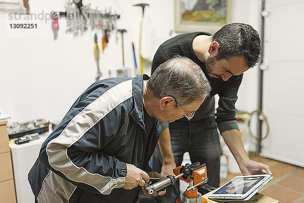 Mechaniker beobachten Tablet-Computer bei der Bedienung von Geräten in der Werkstatt