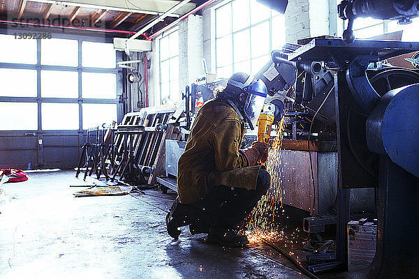 Arbeiter schneidet Eisen mit elektrischer Säge in der Fabrik