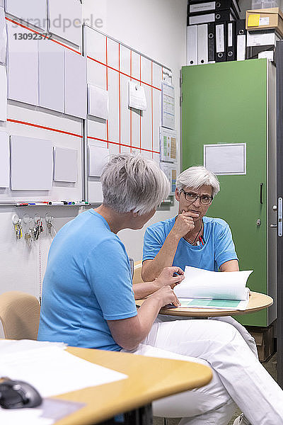 Ärztinnen besprechen Krankenakten  während sie in einer medizinischen Klinik sitzen