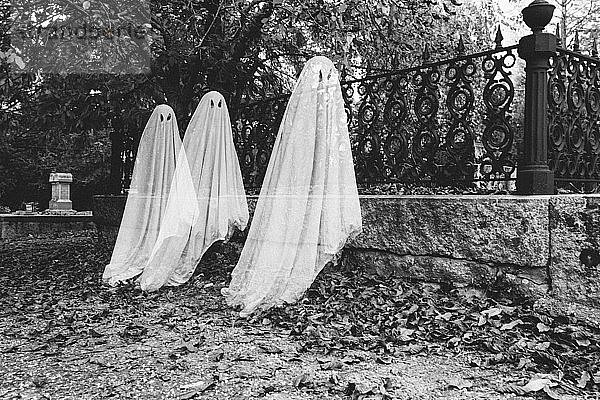 Doppelbelichtung von Jungen in Geisterkostümen auf dem Friedhof zu Halloween