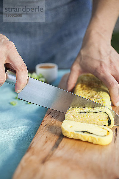 Mittelteil einer Köchin beim Schneiden von gebackenem Gebäck in der Großküche