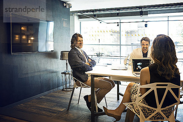 Geschäftsleute lächeln während einer Besprechung im Büro