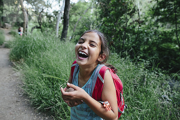 Porträt eines im Wald stehenden lachenden Mädchens
