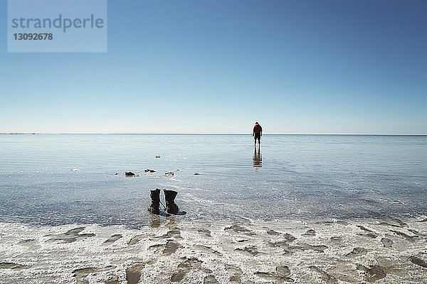 Mitteldistanz eines am Strand stehenden Mannes gegen den Himmel