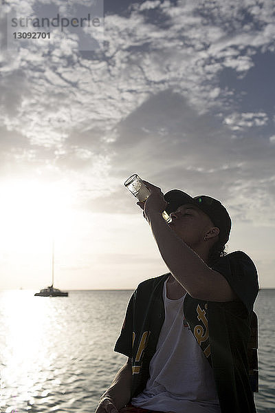 Junger Mann trinkt Bier auf dem Seeweg