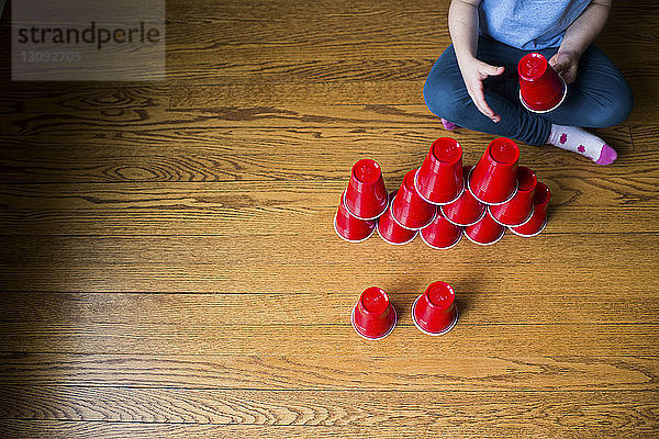 Hochwinkelaufnahme eines Mädchens  das zu Hause mit Plastikbechern spielt